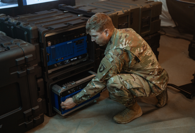 Militair medewerker werkt aan een open 19 inch SKB shock rack met geïntegreerde elektronica, omringd door meerdere gesloten 19 inch SKB racks in een operationele omgeving