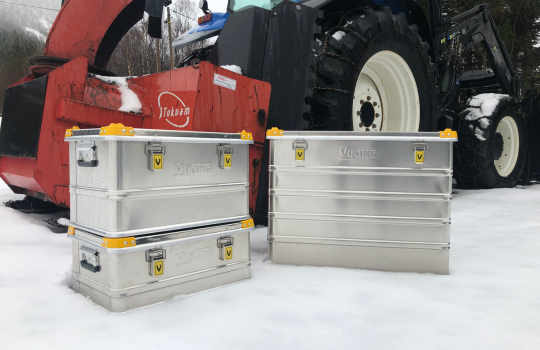 Aluminium kisten van Viking in de sneeuw, geplaatst naast een landbouwmachine