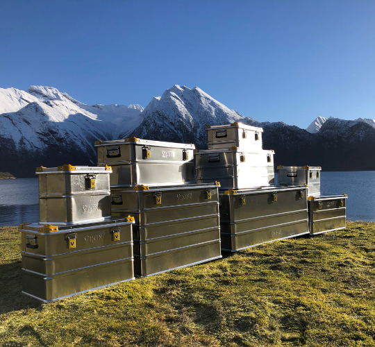 Gestapelde aluminium kisten van Viking in een bergachtig landschap aan een meer